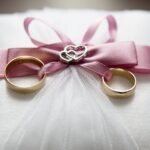 selective focus photography of silver colored engagement ring set with pink bow accent on throw pillow